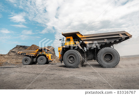 Large quarry dump truck. Big yellow mining truck at work site. Loading coal into body truck. Production useful minerals. Mining truck mining machinery to transport coal from open-pit production 83316767