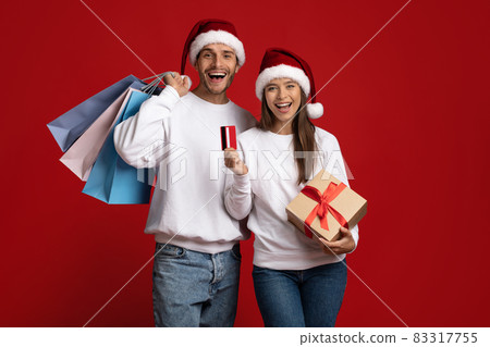Christmas Shopping. Joyful Couple In Santa Hats With Gift And Credit Card Christmas Shopping. Joyful Couple In Santa Hats With Gift And Credit Card 83317755