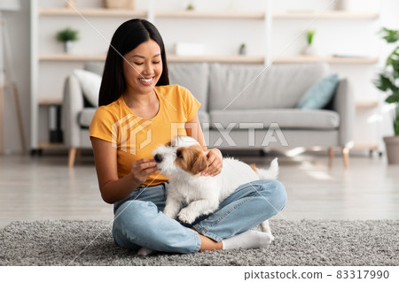 Joyful japanese lady giving her doggy treats at home 83317990