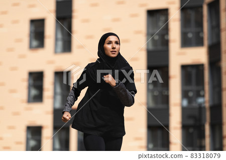 Muslim Jogger. Young Islamic Female In Modest Sportswear Running Outdoors Muslim Jogger. Young Islamic Female In Modest Sportswear Running Outdoors 83318079