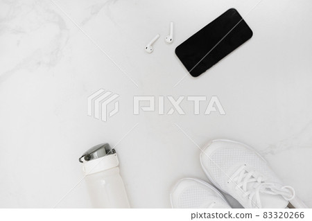 Top view of sneakers, water bottle, smartphone with earphones on white background. 83320266