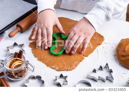 Making gingerbread cookies, child cuts dough with Christmas mold on table, horizontal Making gingerbread cookies, child cuts dough with Christmas mold on table, horizontal 83321005