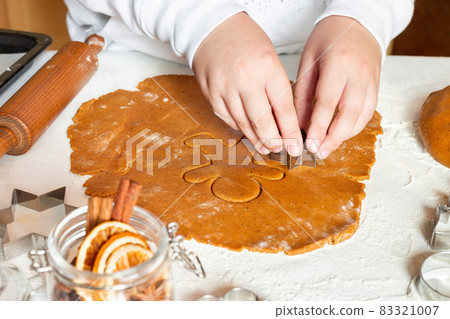 Making gingerbread cookies. Child cuts dough with Christmas mold on table, horizontal 83321007