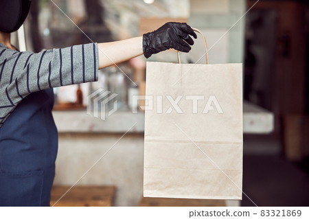 Woman cafe worker serving unrecognizable customer outdoors 83321869