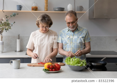 Happy bonding middle aged couple cooking at home. Happy bonding middle aged couple cooking at home. 83322396