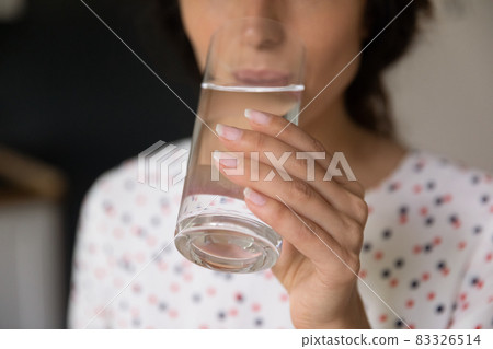 Hand of woman holding glass and drinking fresh cold water 83326514
