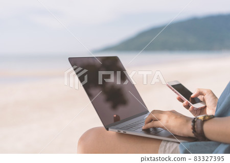 Woman using laptop and smart phone on tropical beach background. Woman using laptop and smart phone on tropical beach background. 83327395
