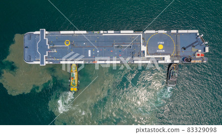 Aerial view car carrier and tugboat at car shipping out of trade port, Large RoRo (Roll on/off) vessel at sea. 83329098