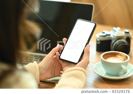 Over shoulder view of young woman holding smart phone with empty display. 83329178
