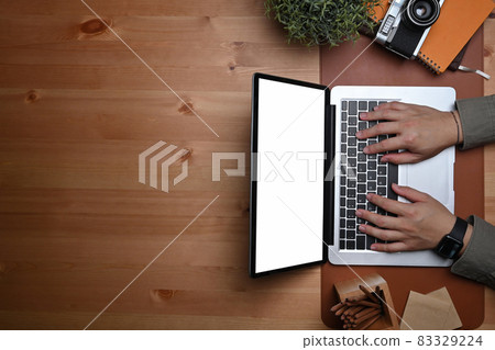 Above view young man working with laptop computer on wooden table. 83329224