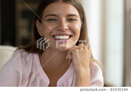 Happy pretty young woman looking at camera with toothy smile Happy pretty young woman looking at camera with toothy smile 83330194