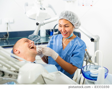 Dentist inspects male patient teeth 83331030