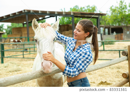 Female farmer caressing horse 83331381