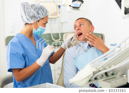 Businessman complains of toothache to dentist 83333161
