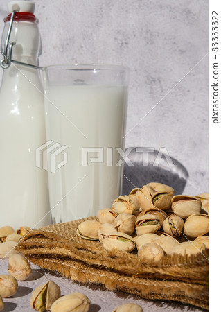 Glass of healthy pistachio milk stands on concrete background. Diet milk, vegetarian food. Gluten free. Close-up. Pistachio lactose free milk for dietary nutrition. Alternative food and vegetarianism. Glass of healthy pistachio milk stands on concrete background. Diet milk, vegetarian food. Gluten free. Close-up. Pistachio lactose free milk for dietary nutrition. Alternative food and vegetarianism. 83333322