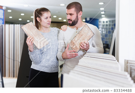 Positive couple holding sample of kitchen ceramic tile 83334488