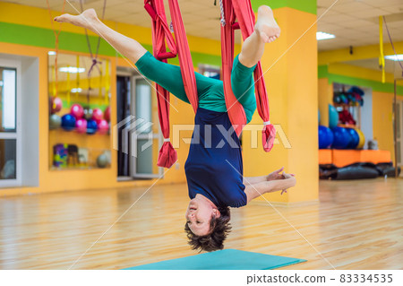 Senior mature woman practices anti-gravity yoga with a hammock in a studio. Lifestyle 83334535