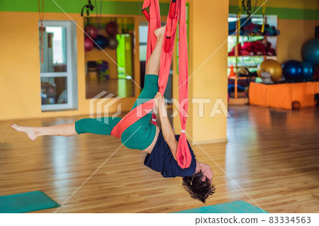 Senior mature woman practices anti-gravity yoga with a hammock in a studio. Lifestyle 83334563