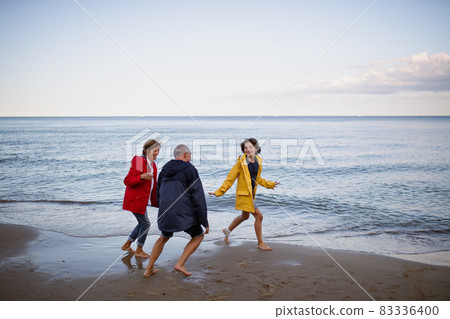 Senior couple and their preteen granddaughter running and having fun on sandy beach. Senior couple and their preteen granddaughter running and having fun on sandy beach. 83336400