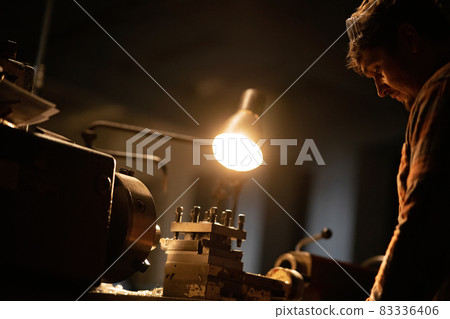 Industrial man working indoors in metal workshop at night. 83336406