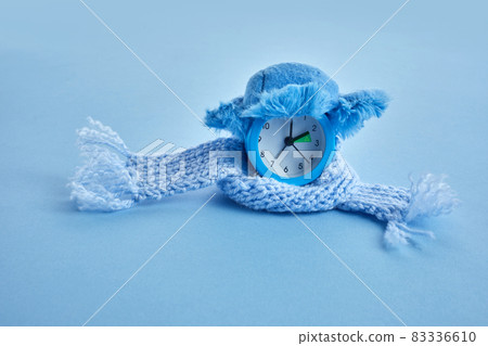 Clock changing from summer to winter time. Alarm clock with winter hat Clock changing from summer to winter time. Alarm clock with winter hat 83336610