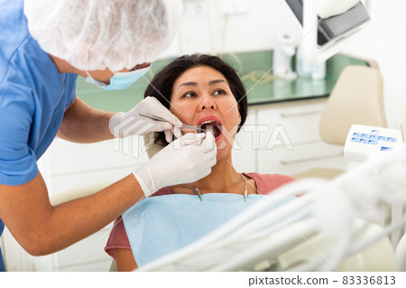 Focused man dentist in a protective mask treats a woman patient Focused man dentist in a protective mask treats a woman patient 83336813