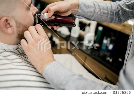 client in the salon cuts his beard. client in the salon cuts his beard. 83336896