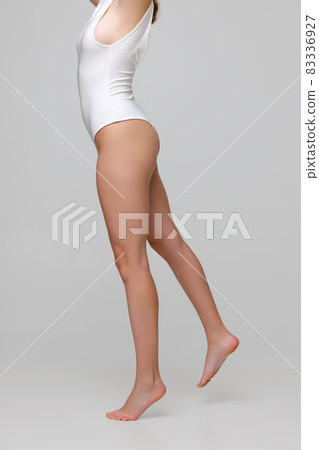 Cropped image of female body, back view in white bodysuit isolated over gray background. Standing on tiptoe Cropped image of female body, back view in white bodysuit isolated over gray background. Standing on tiptoe 83336927