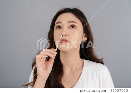 woman using coronavirus(covid-19) rapid antigen self test kit (atk) at home with cotton nasal swab 83337920