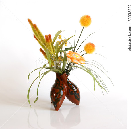 Decorative ceramic vase with a bouquet of artificial flowers on a white background 83338322