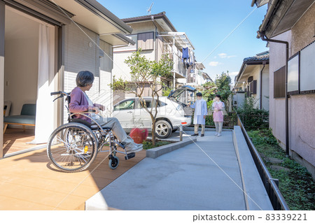 Visiting medical care: An elderly woman in a wheelchair welcoming a teacher and a nurse 83339221