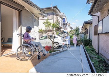 Visiting medical care: An elderly woman in a wheelchair welcoming a teacher and a nurse 83339222