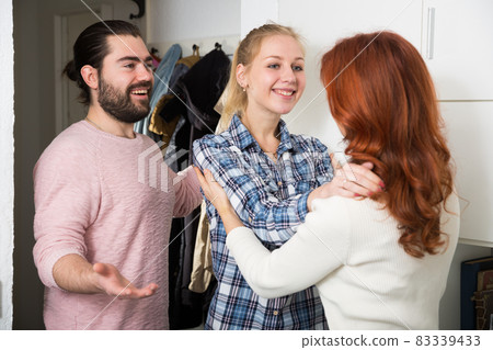 Mother and adult children standing near door and hugging at home Mother and adult children standing near door and hugging at home 83339433