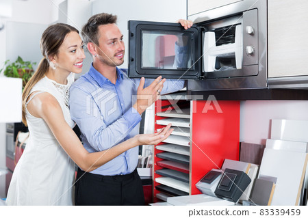 Happy young couple looking new microwave 83339459