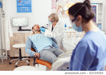 Senior stomatologist holding sterilized dental tools talking with sick patient 83339565
