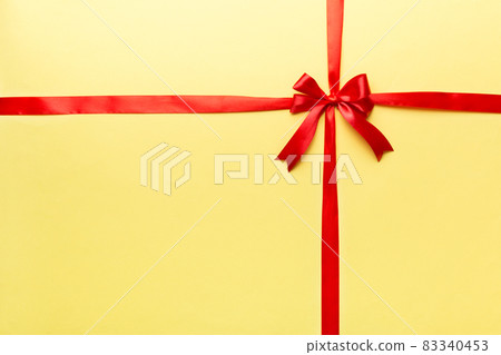 Top view of Red ribbon rolled and red bow isolated on colored background. Flat lay with copy space 83340453