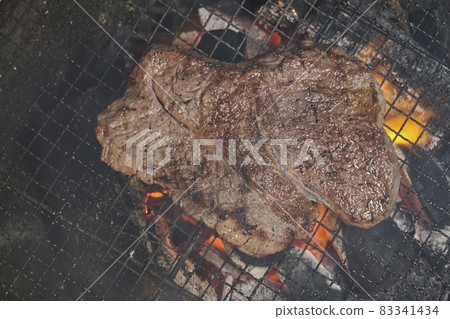 Thick-sliced steak dripping gravy over charcoal 83341434