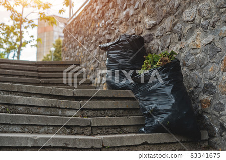 full black garbage bags with trash at city park outdoor after clean up 83341675