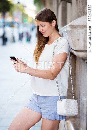 Young woman standing with phone near building Young woman standing with phone near building 83341825