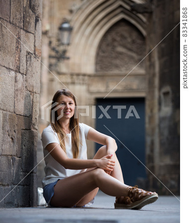 Young woman sitting near old stone wall 83341868