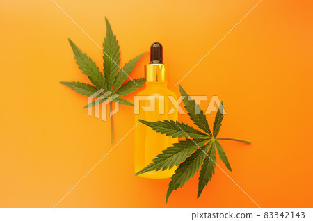 Cannabis cbd oil and green leaves on grey background. Cannabis cbd oil and green leaves on grey background. 83342143