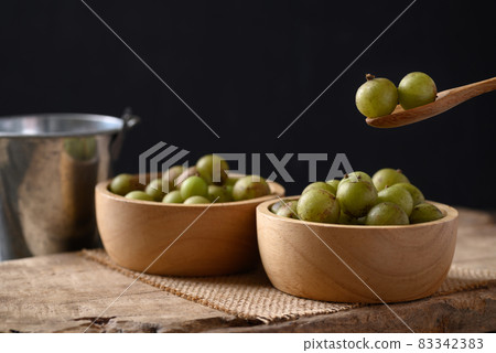Wild Indian gooseberry or amla in a bowl with spoon on black background Wild Indian gooseberry or amla in a bowl with spoon on black background 83342383