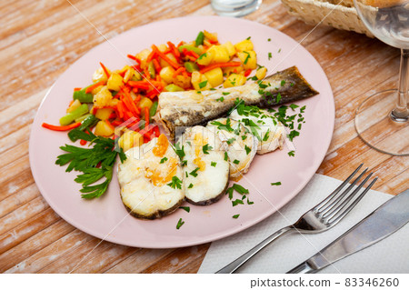 Oven baked hake with vegetable garnish 83346260