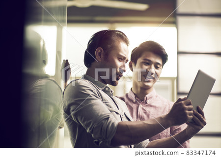 two asian businessmen working together in office looking at digital tablet two asian businessmen working together in office looking at digital tablet 83347174