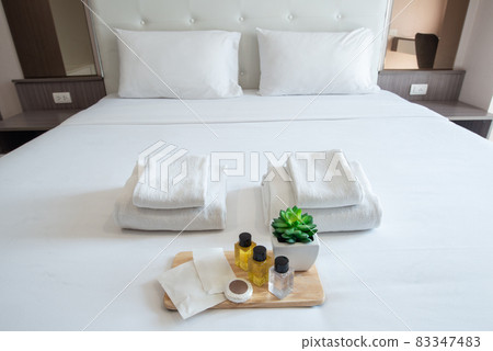 Set of hotel amenities (such as towels, shampoo, soap, gel etc) on the bed. Hotel amenities is something of a premium nature provided in addition to the room when renting a room. 83347483