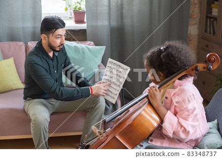 Confident music teacher pointing at paper with notes during home lesson Confident music teacher pointing at paper with notes during home lesson 83348737