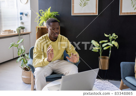 Young confident African-American man sitting in front of laptop Young confident African-American man sitting in front of laptop 83348865