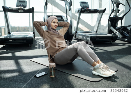 Young woman making sit-ups on the floor of gym Young woman making sit-ups on the floor of gym 83348982