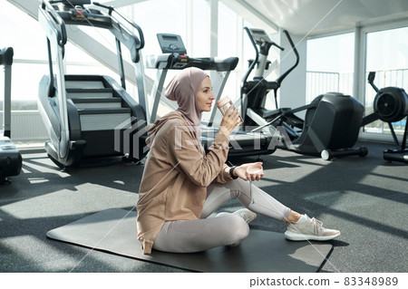 Young serene sportswoman drinking water after training 83348989