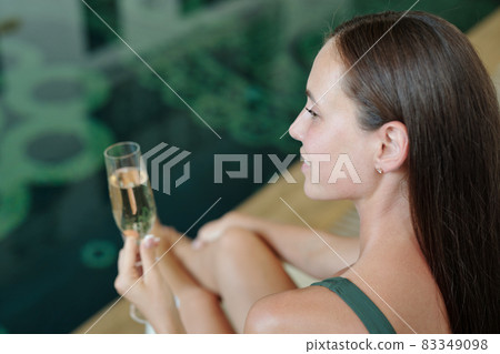 Young brunette woman holding glass of champagne Young brunette woman holding glass of champagne 83349098